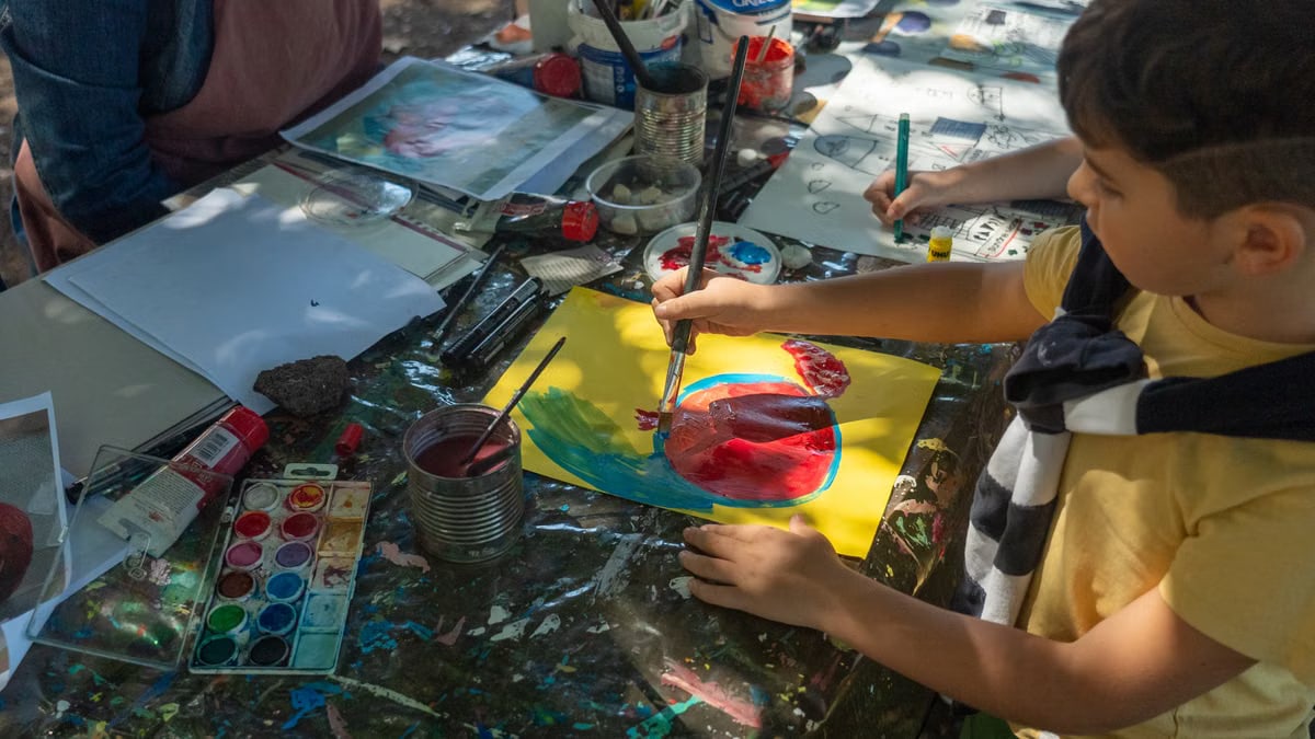 A child painting creatively with watercolors during an outdoor art class.